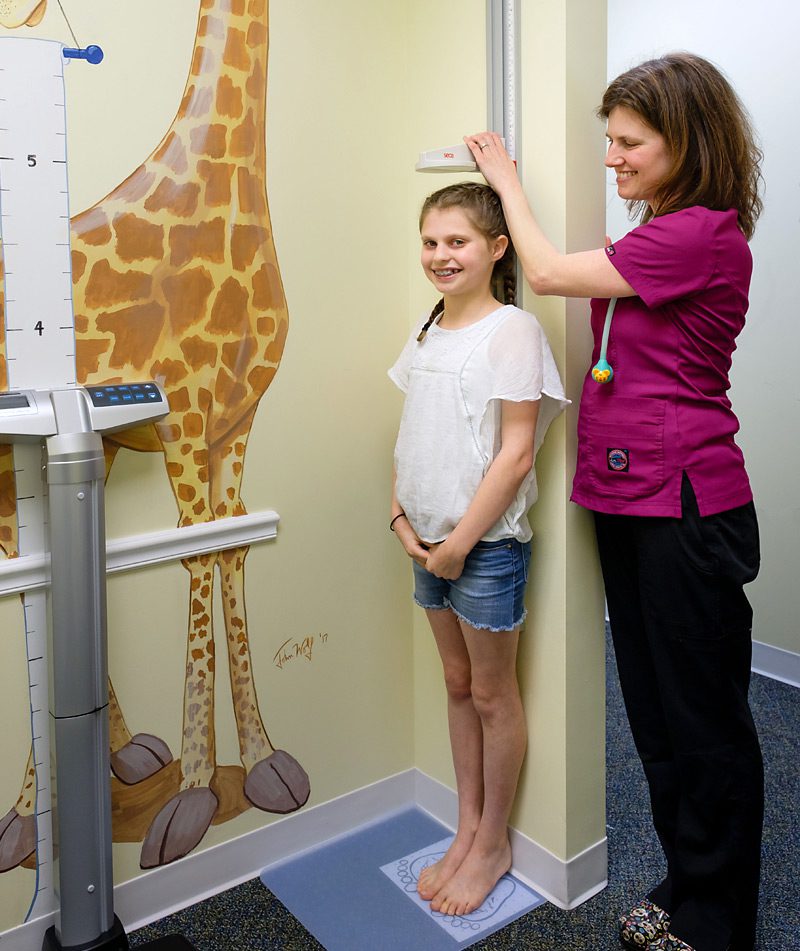Girl having her height measured by a doctor. Girl having her height measured by a doctor.